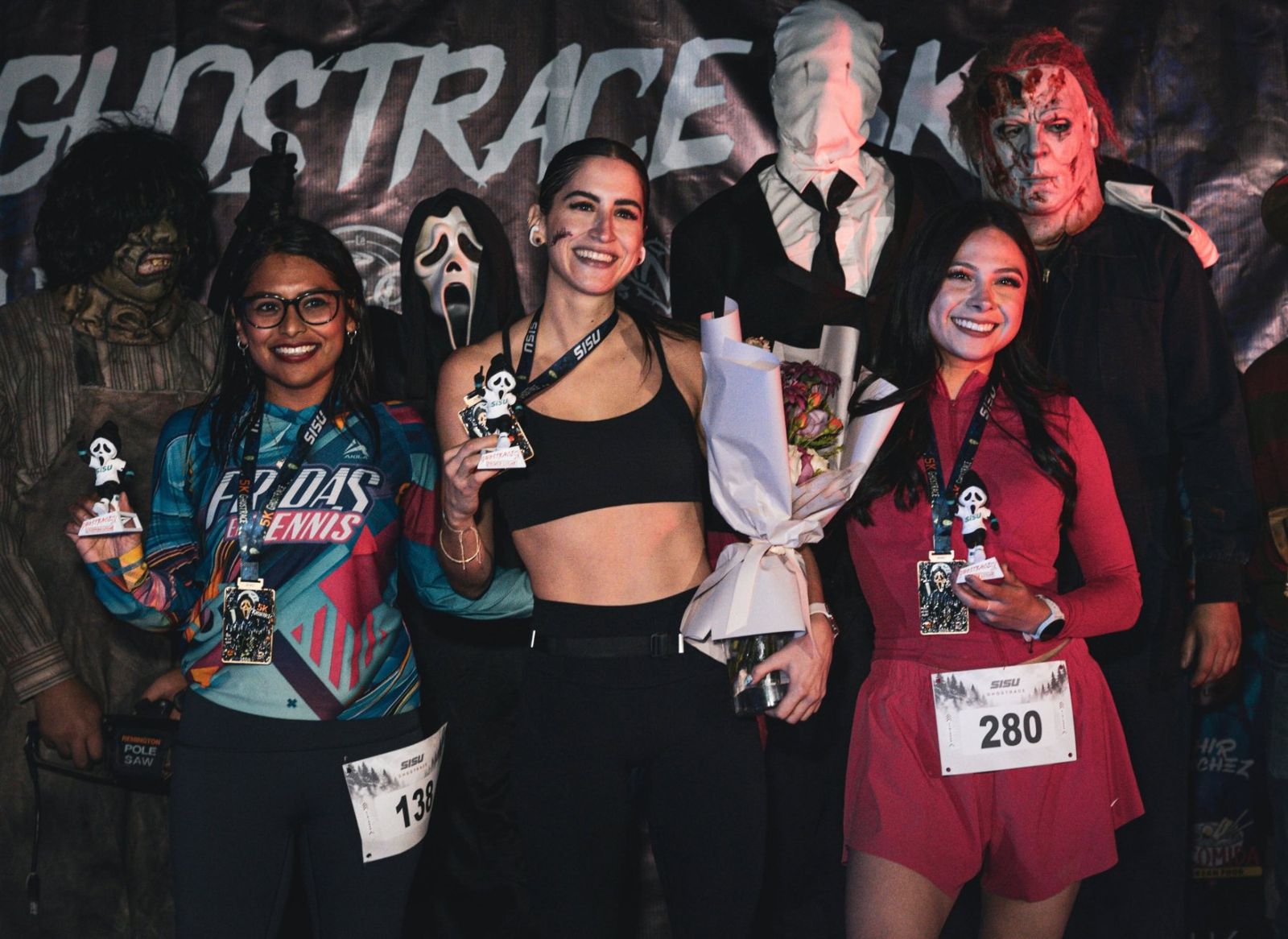 Corredoras con su medalla en el podio de GhostRace 5K de SISU