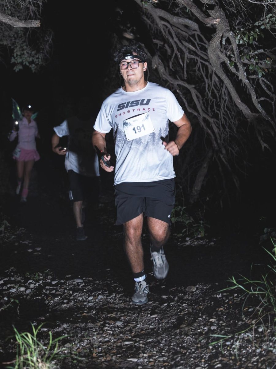Corredor con lámpara frontal en el sendero nocturno de GhostRace
